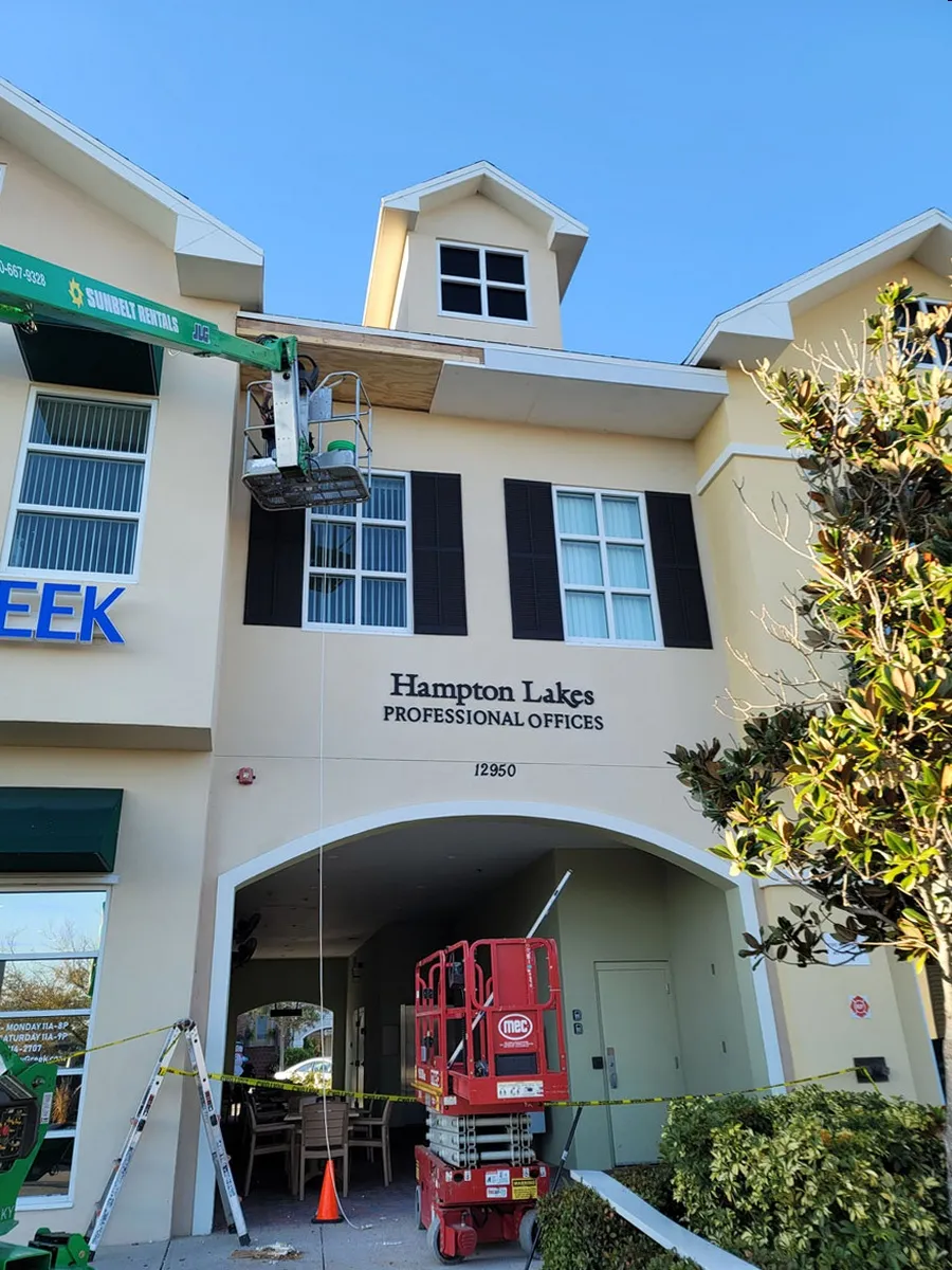 Commercial office building exterior renovation by Florida building contractor with boom lift and construction equipment on site