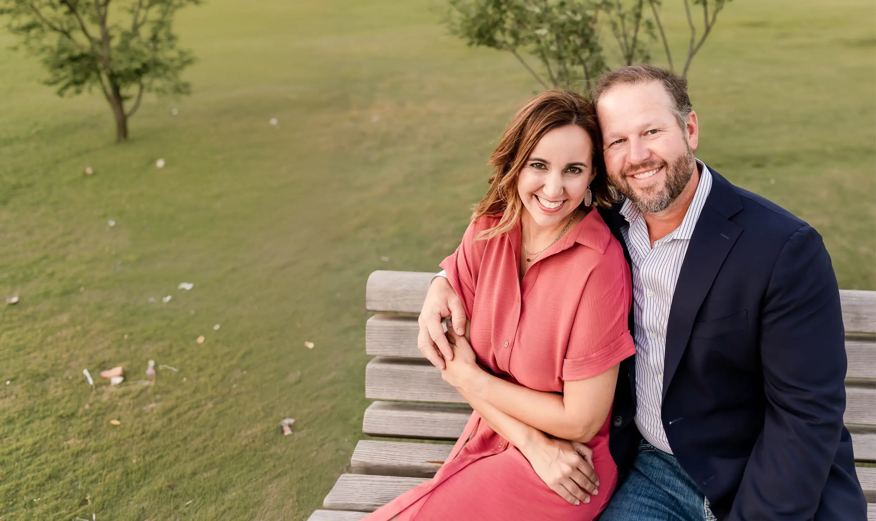 A smiling couple sitting close together on a park bench