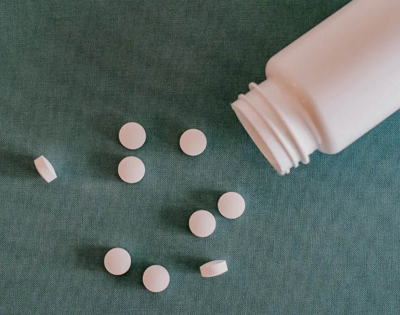 Tablets spilled from a medicine bottle on a fabric surface