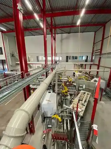 Kabelski most z množico sivih in zelenih PROFINET kablov v industrijski hali z rdečo jekleno konstrukcijo