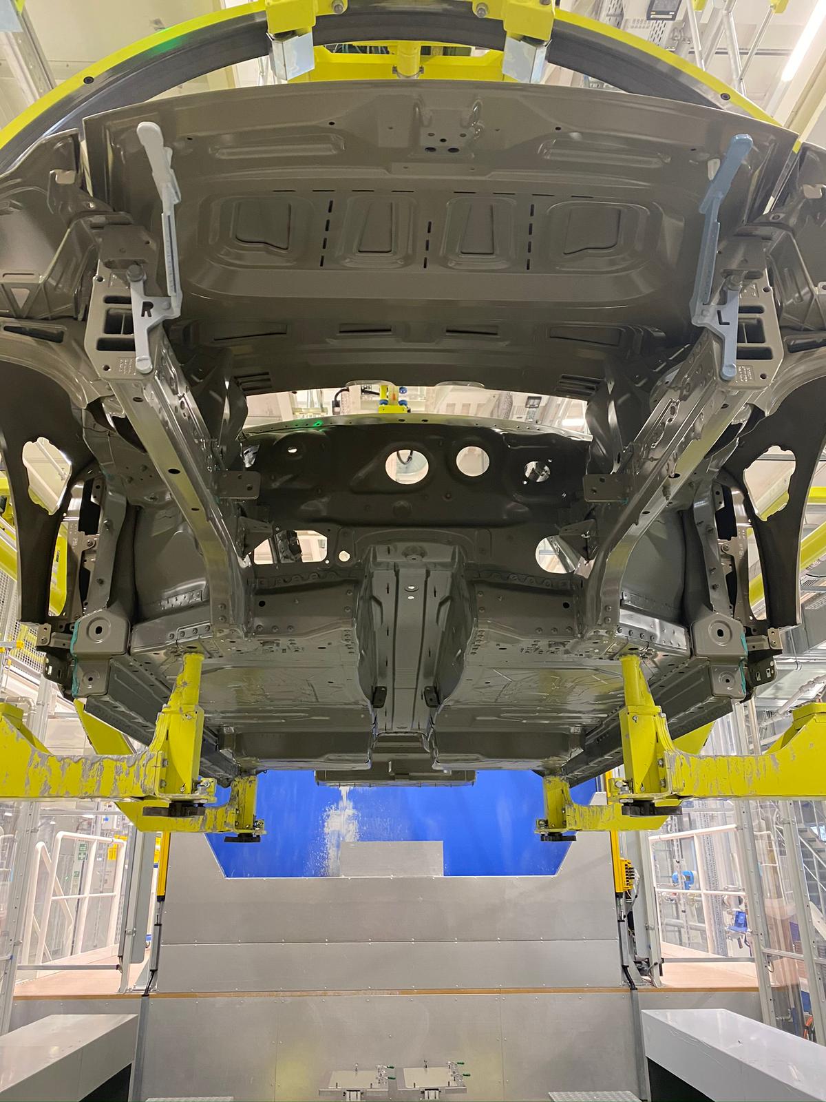 Pogled od spodaj na karoserijo avtomobila vpeto v rumen Eisenmann rotacijski sistem med postopkom lakiranja