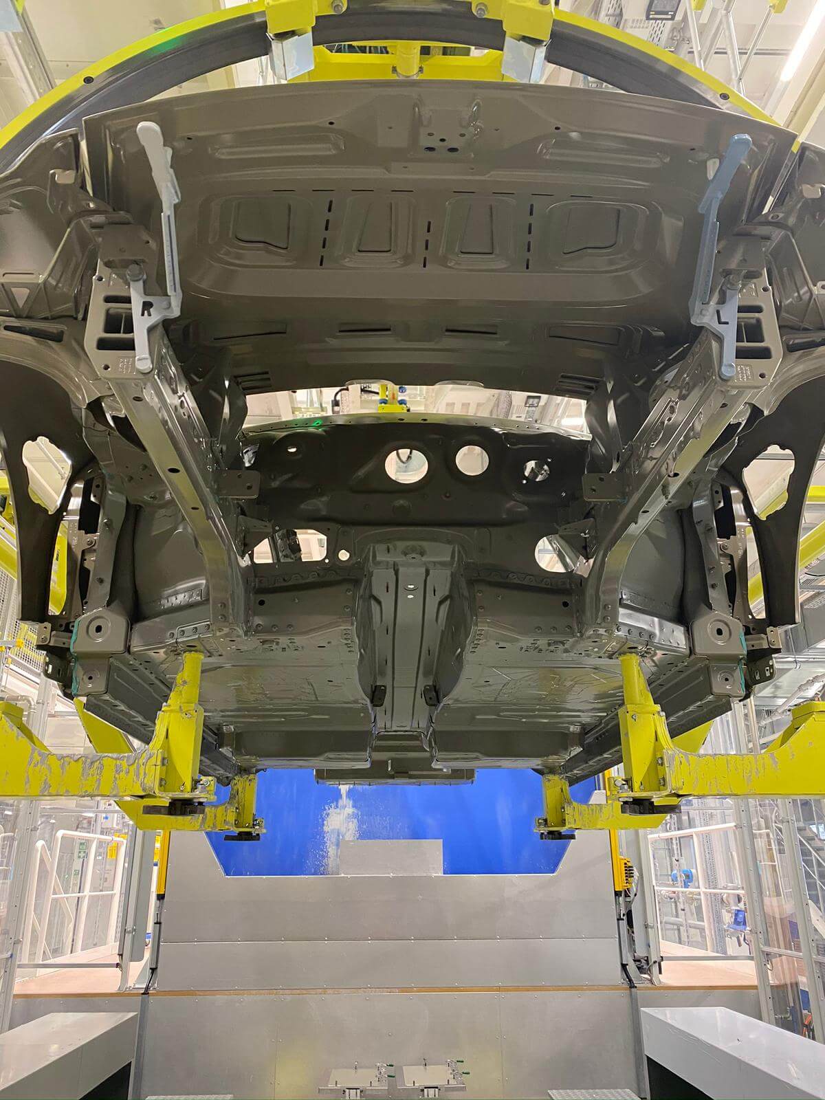 Pogled od spodaj na karoserijo avtomobila vpeto v rumen Eisenmann rotacijski sistem med postopkom lakiranja