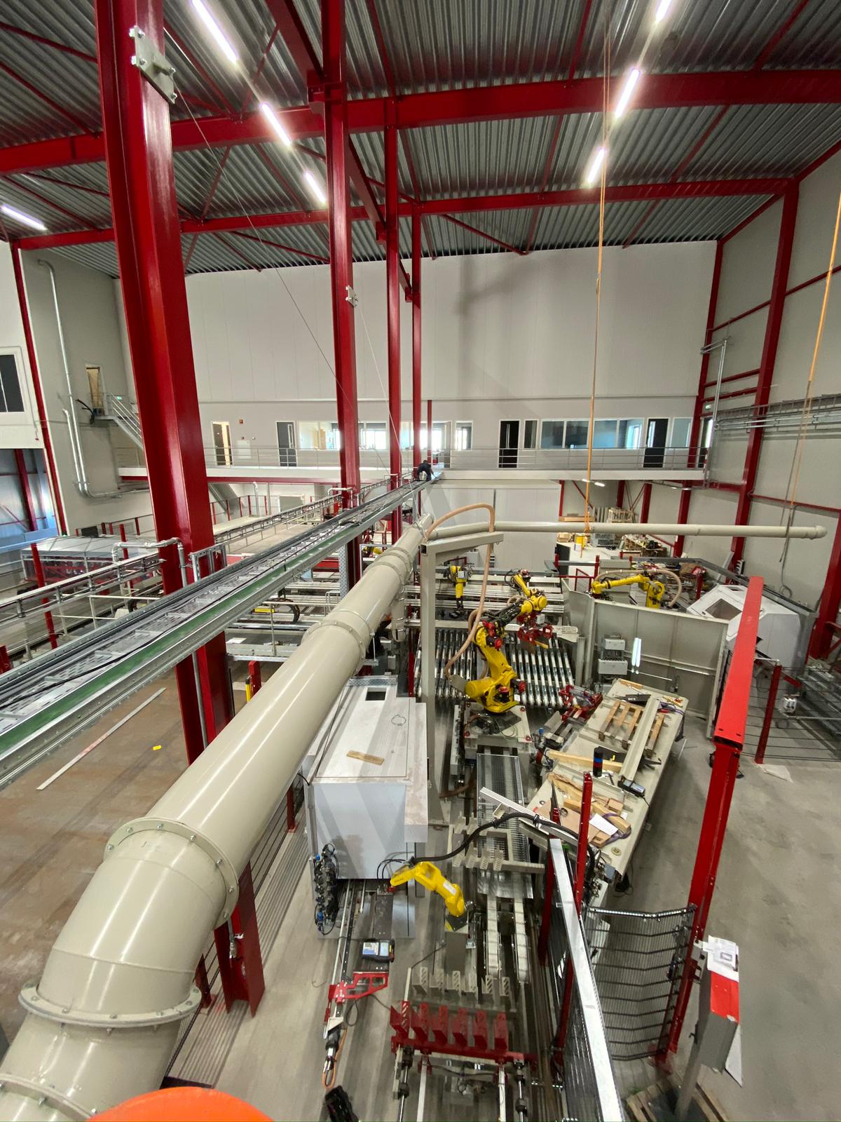 Kabelski most z množico sivih in zelenih PROFINET kablov v industrijski hali z rdečo jekleno konstrukcijo