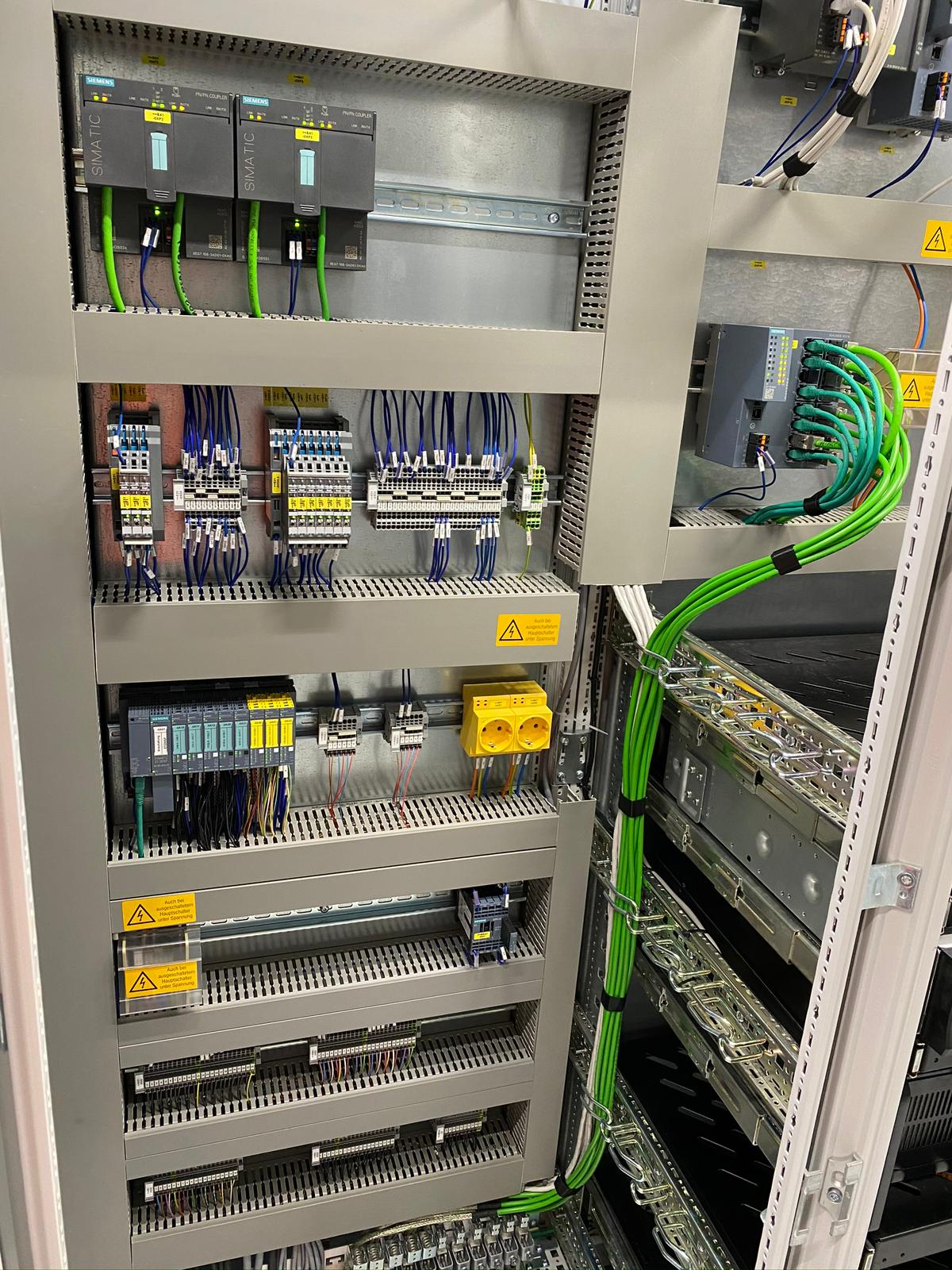 Električna omarica s Siemens SIMATIC PLC krmilniki, varnostnimi releji, sponkami in PROFINET kabelsko instalacijo za avtomatizacijo industrijske proizvodnje