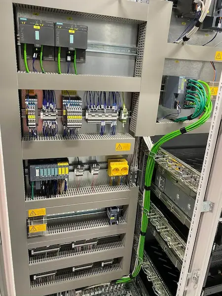 Električna omarica s Siemens SIMATIC PLC krmilniki, varnostnimi releji, sponkami in PROFINET kabelsko instalacijo za avtomatizacijo industrijske proizvodnje