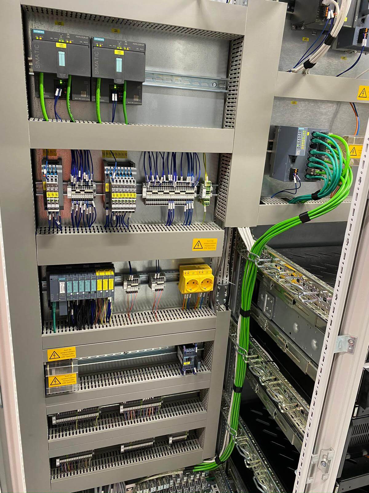 Električna omarica s Siemens SIMATIC PLC krmilniki, varnostnimi releji, sponkami in PROFINET kabelsko instalacijo za avtomatizacijo industrijske proizvodnje