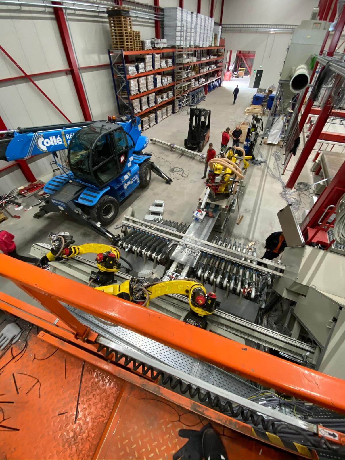 Montaža električno krmiljenih Fanuc robotov na avtomatizirani proizvodni liniji med gradnjo industrijskega obrata s teleskopskim viličarjem Collé