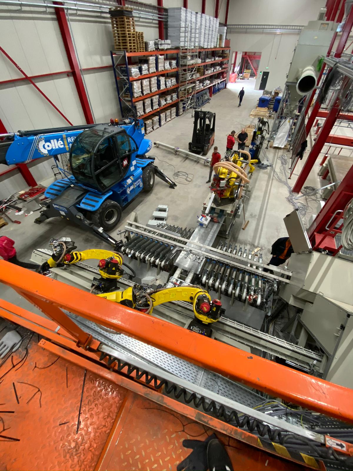 Montaža električno krmiljenih Fanuc robotov na avtomatizirani proizvodni liniji med gradnjo industrijskega obrata s teleskopskim viličarjem Collé