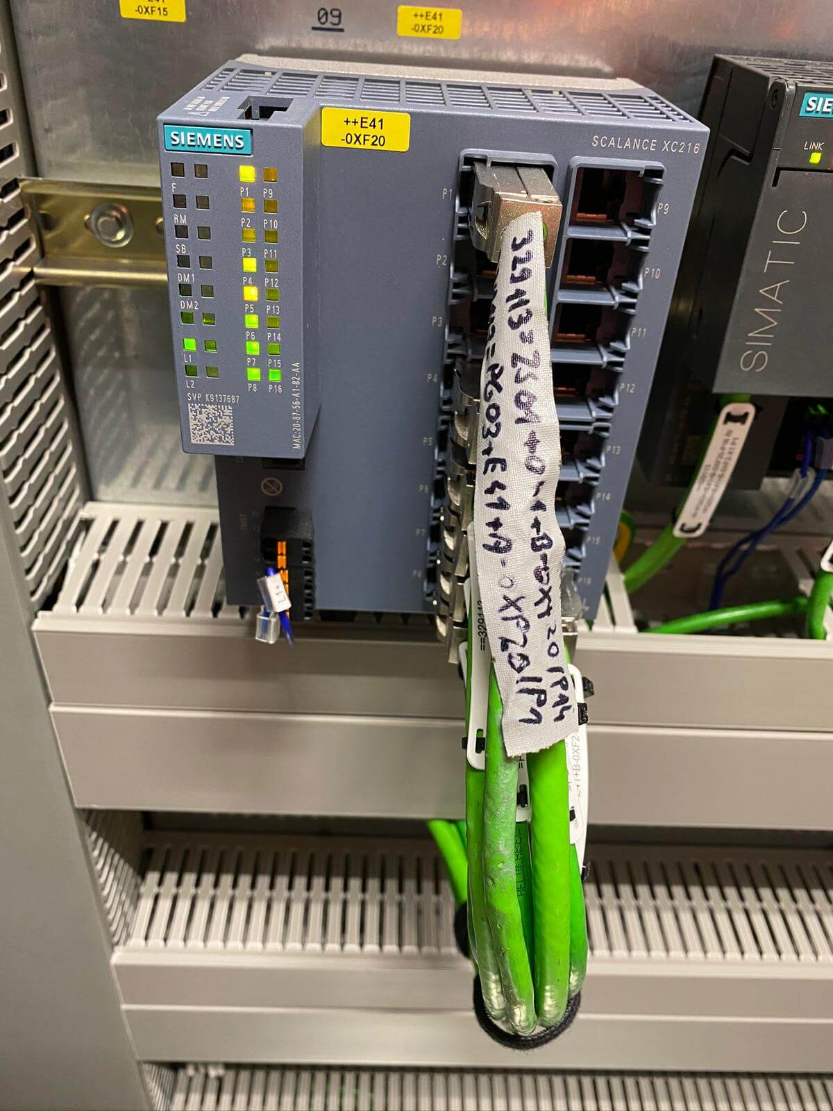 Siemens SCALANCE XC216 industrijski omrežni stikalo s priključenimi zelenimi PROFINET kabli in označenimi priključki