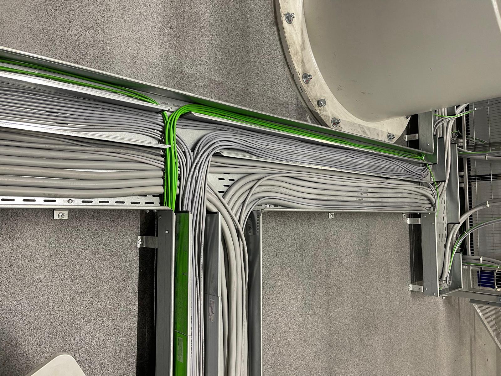 Strokovna električna kabelska instalacija s sivih in zelenih PROFINET kablov na kabelskem mostu ob rotacijskem sistemu za avtomatizacijo industrijske proizvodnje