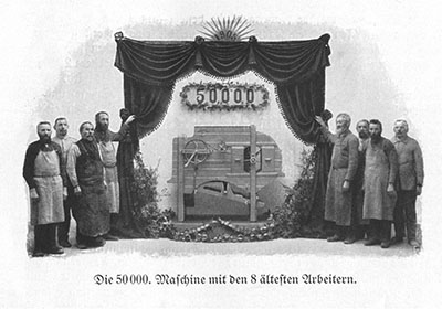 Black and white photo of eight men standing beside a machine with a banner showing 50,000 above it.