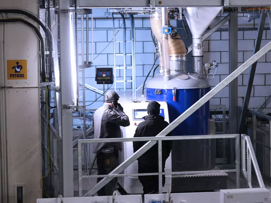 Two workers operating industrial machinery with control panels in a factory setting.