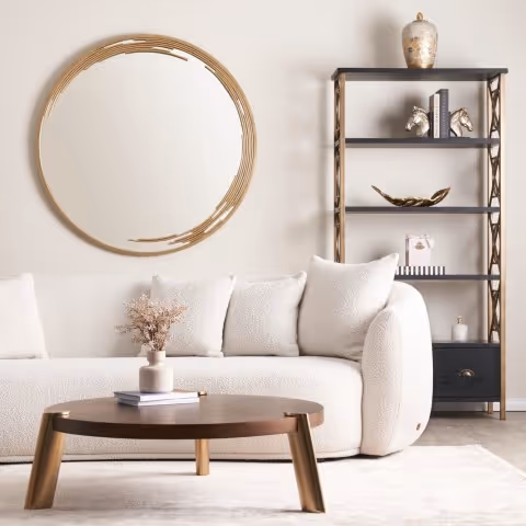 Salon moderne avec canapé blanc, table basse en bois, miroir rond et étagère décorative.