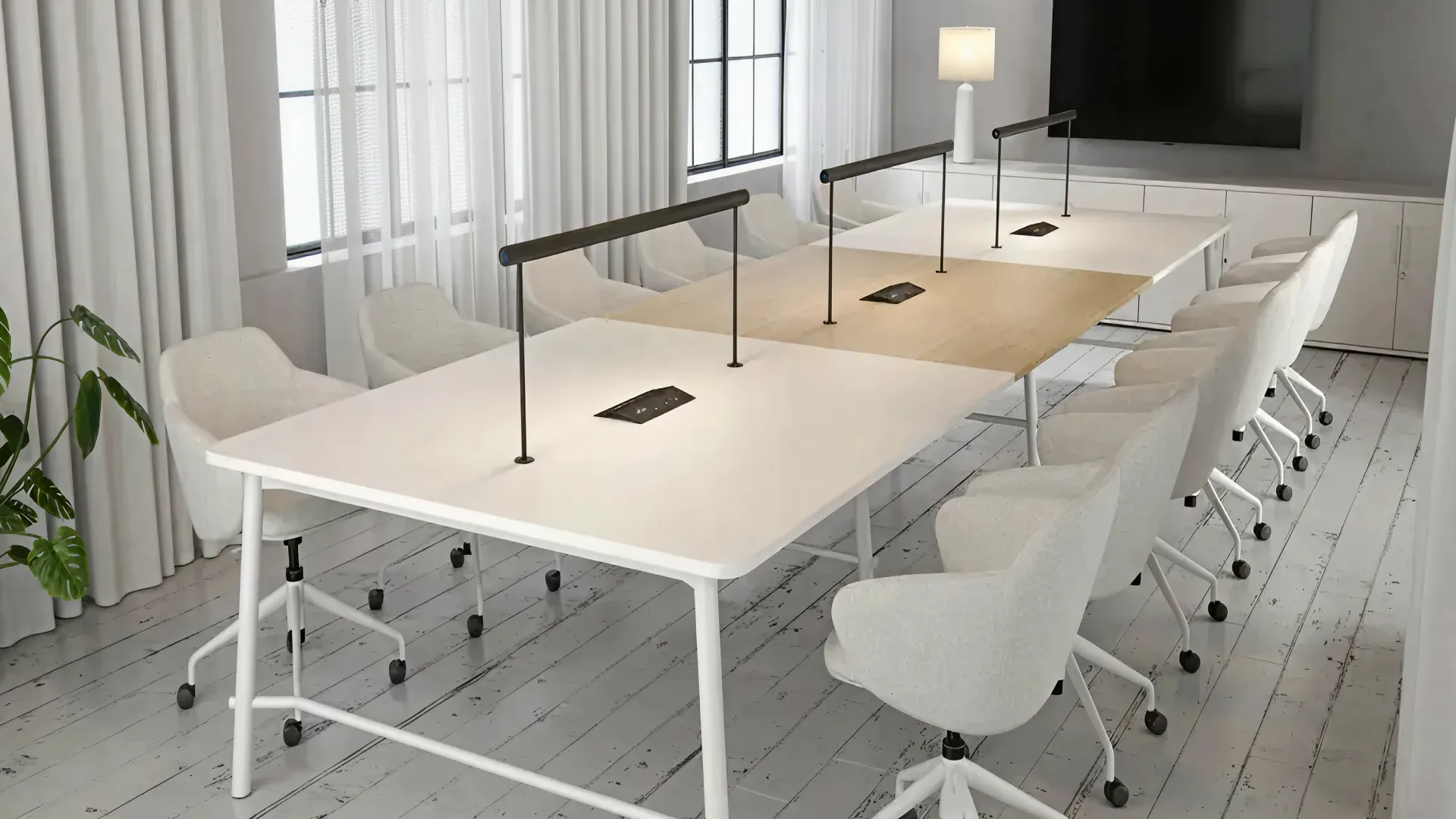 Modern conference room with a long white and wood table, white swivel chairs on casters, table lamps, and a large TV on the wall.