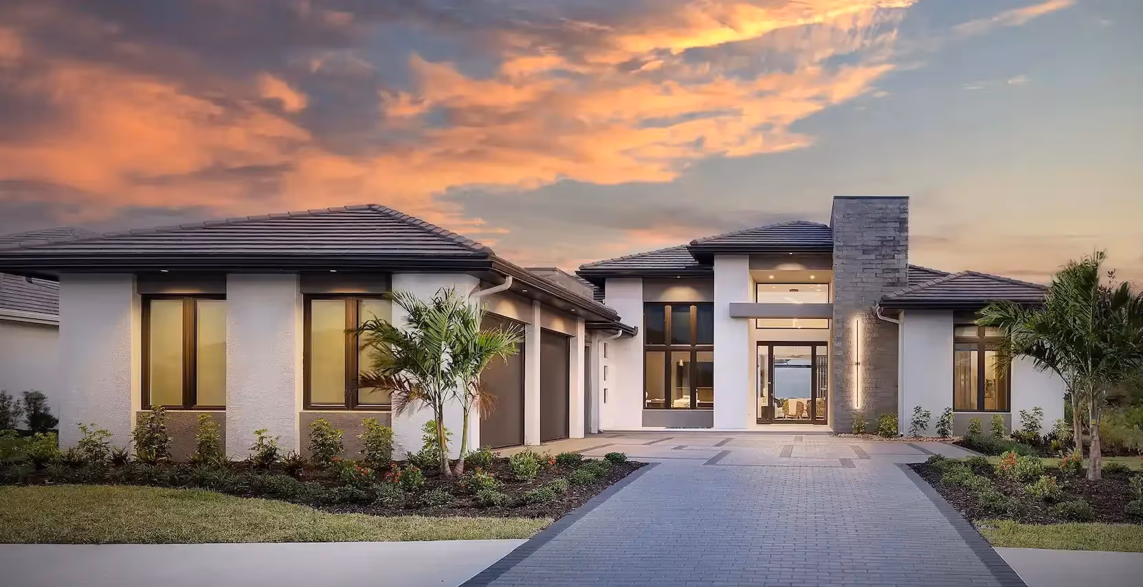 Modern single-story house with a tiled roof, large windows, and a three-car garage at sunset.