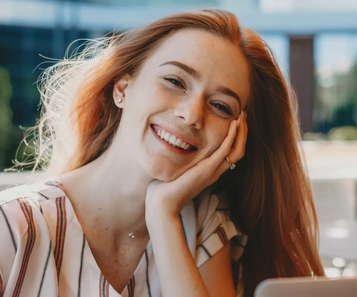 A woman smiling while looking at a tablet.