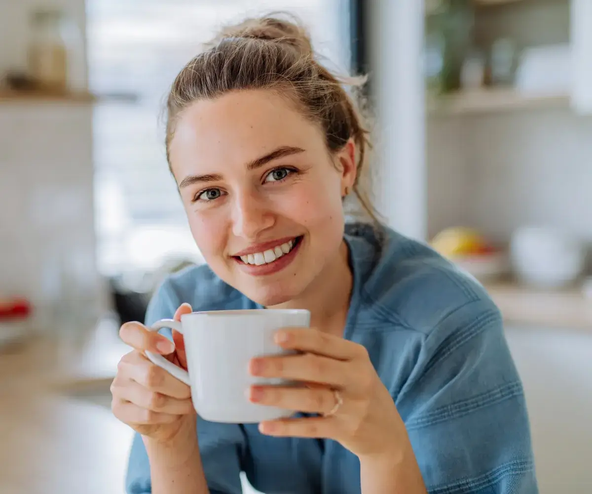 A smiling woman holding a cup of coffee.