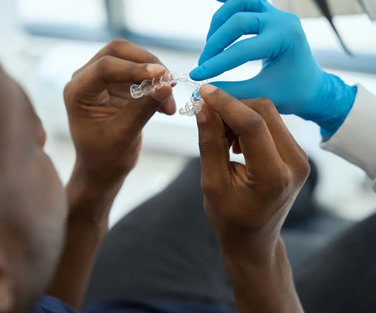 A person in blue gloves is holding a clear object.