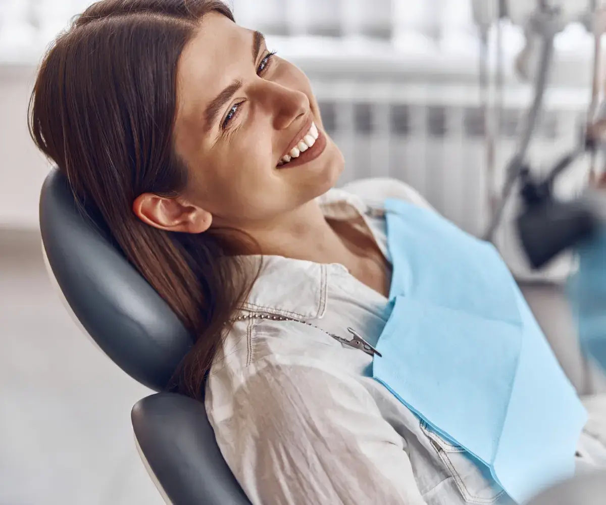 A woman sitting in a dentist chair smiling.