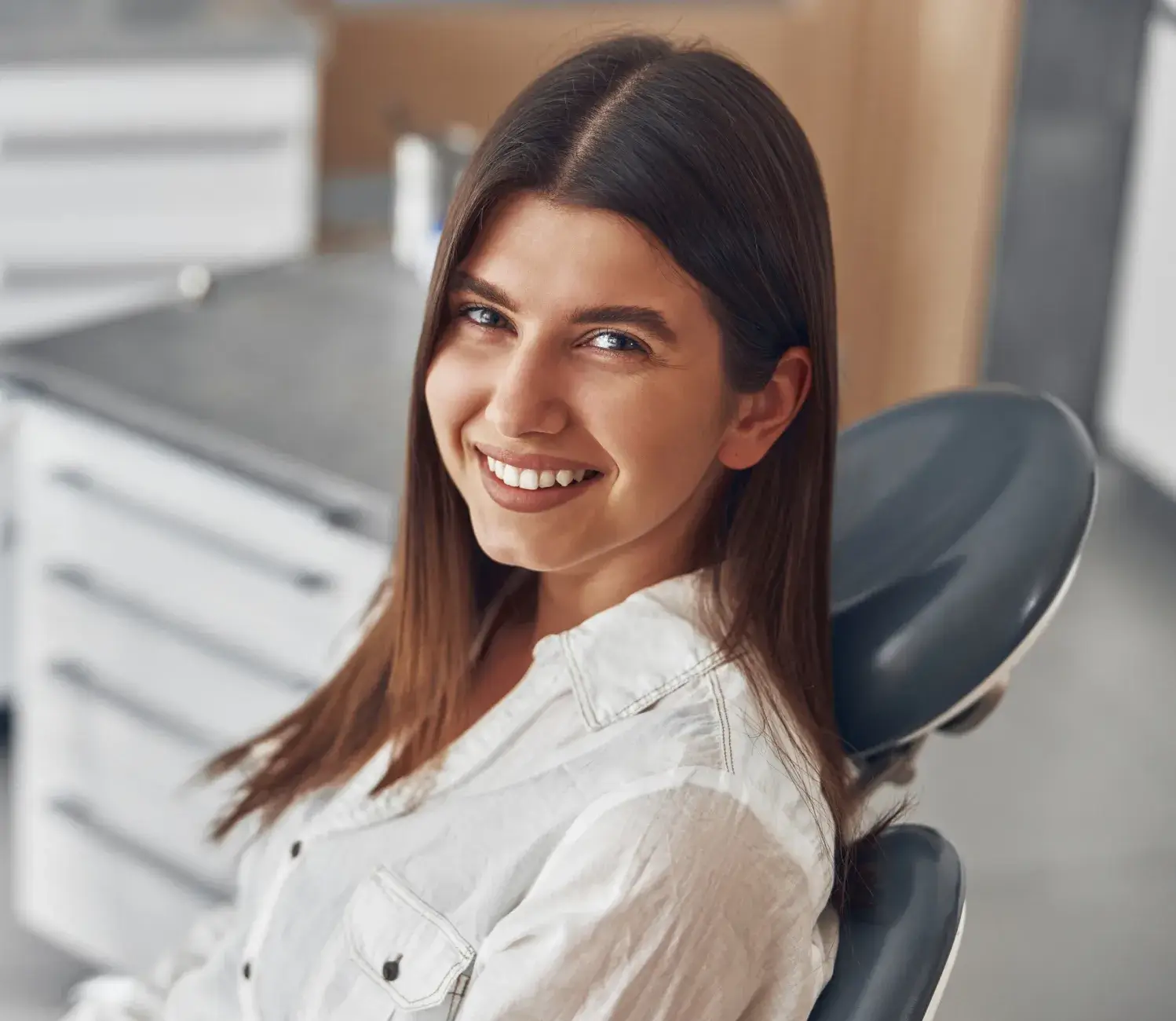 A woman sitting in a dentist chair smiling.