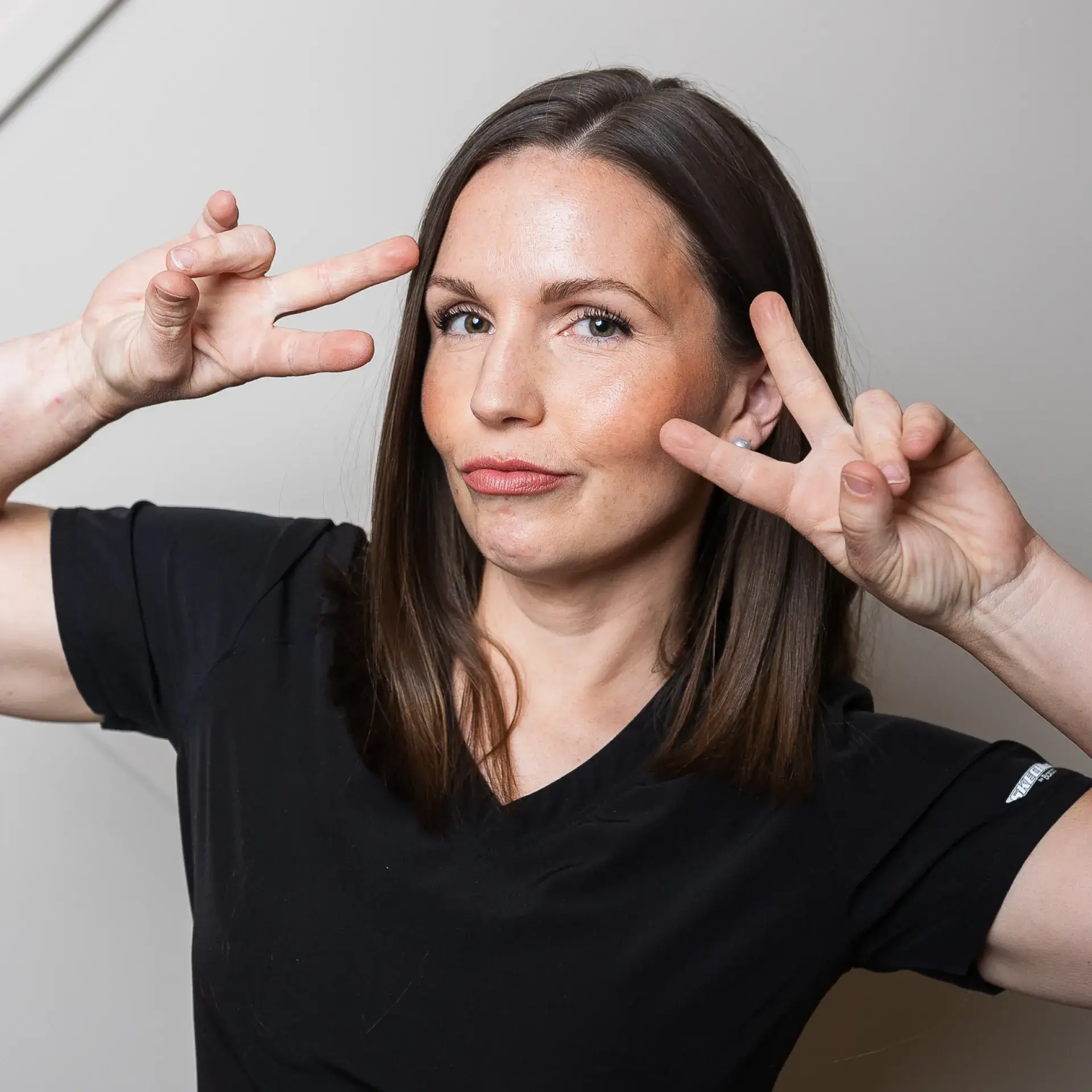 A woman making a peace sign with her fingers.