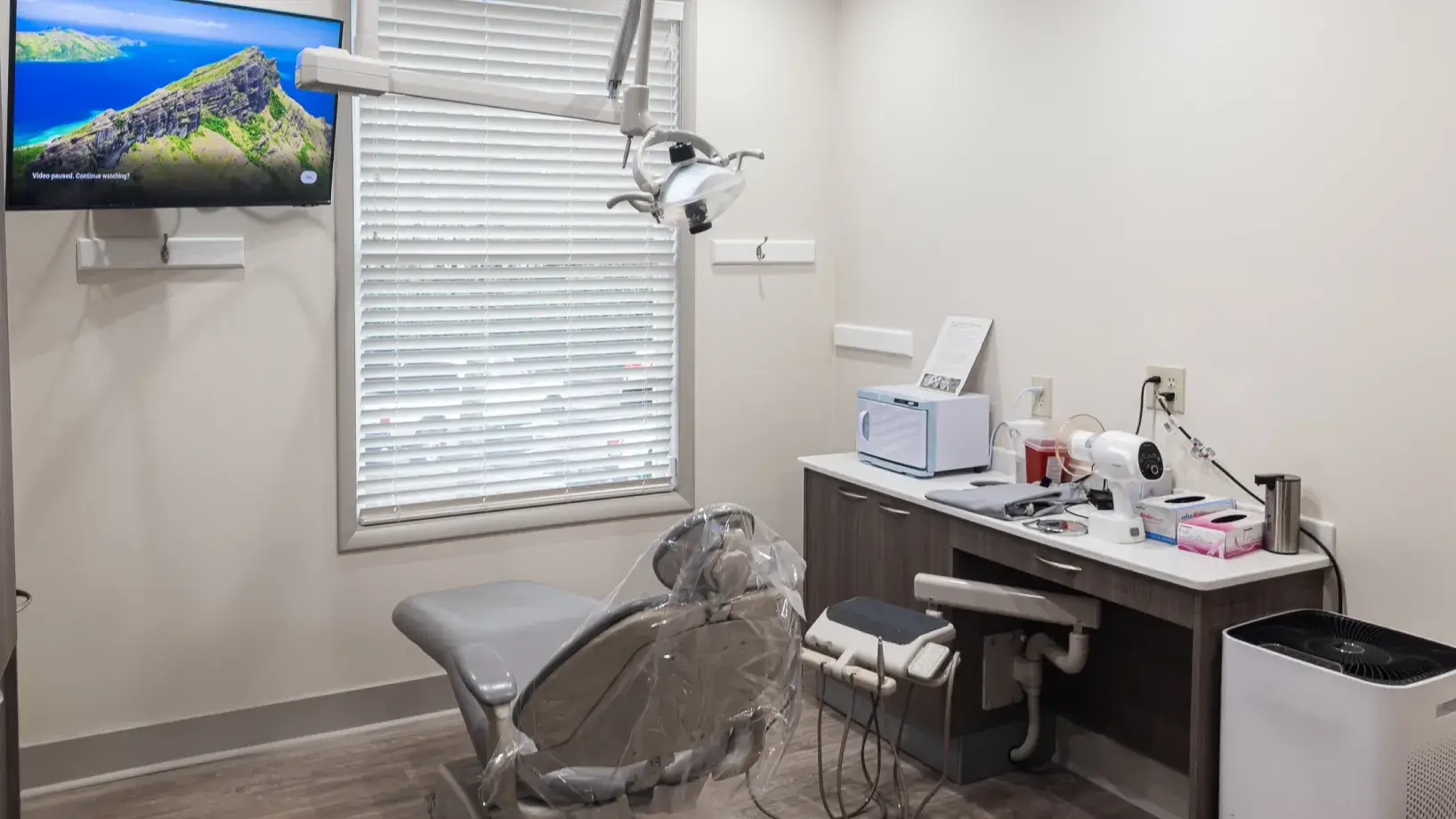 A dentist's office with a tv and a chair.