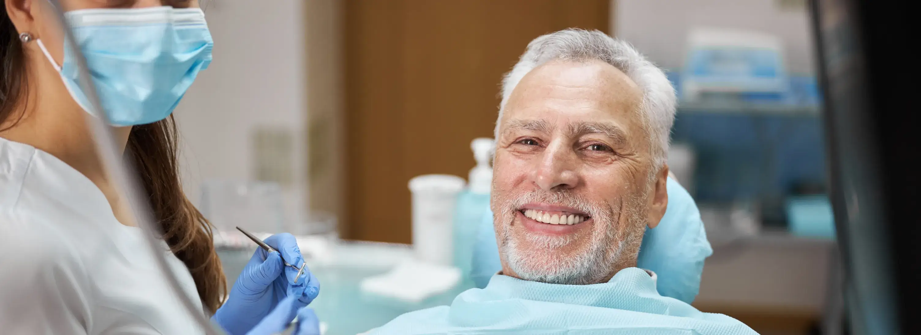 A man in a dentist's chair getting his teeth brushed.