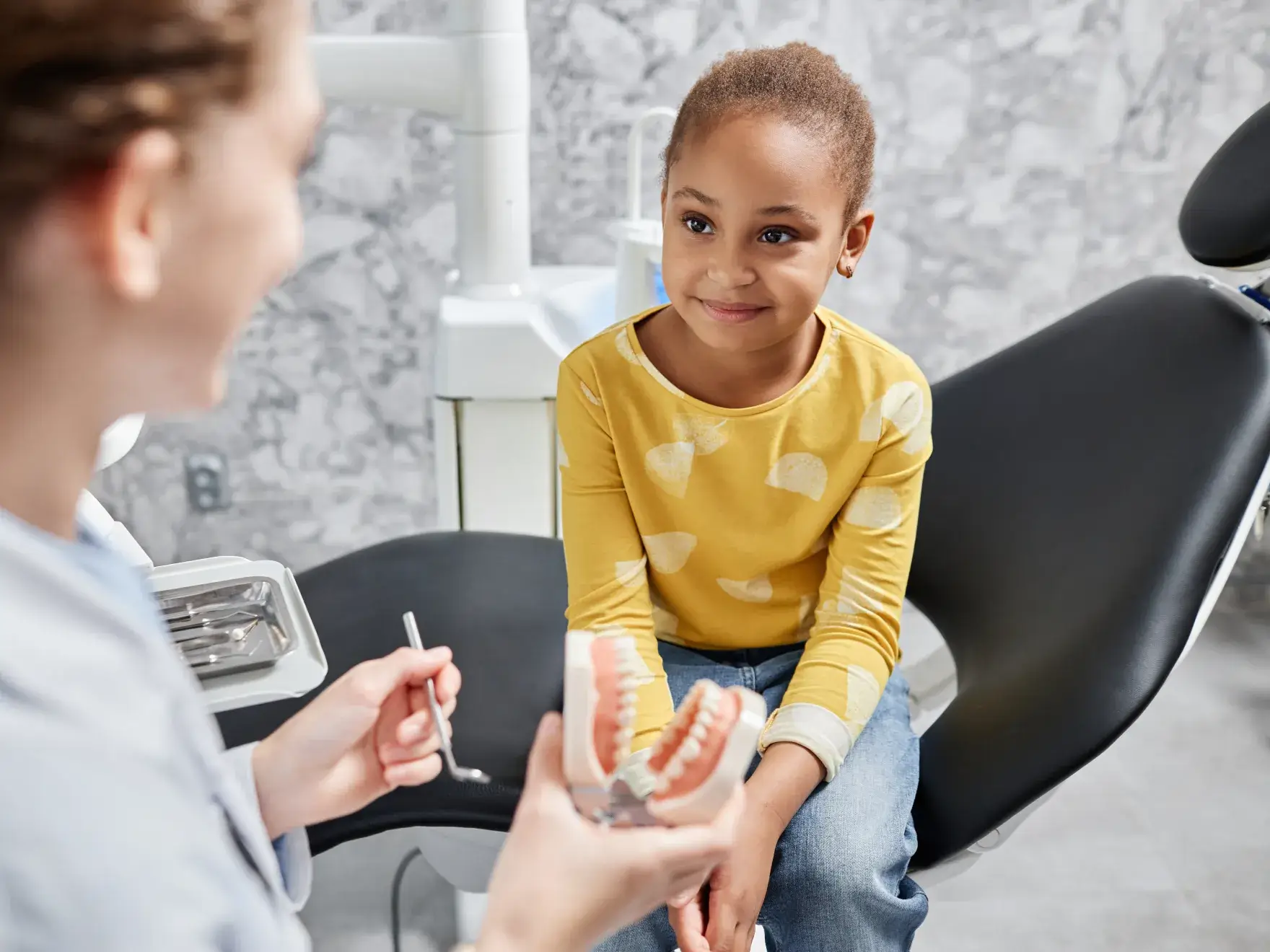 A young girl getting her teeth checked by a dentist.