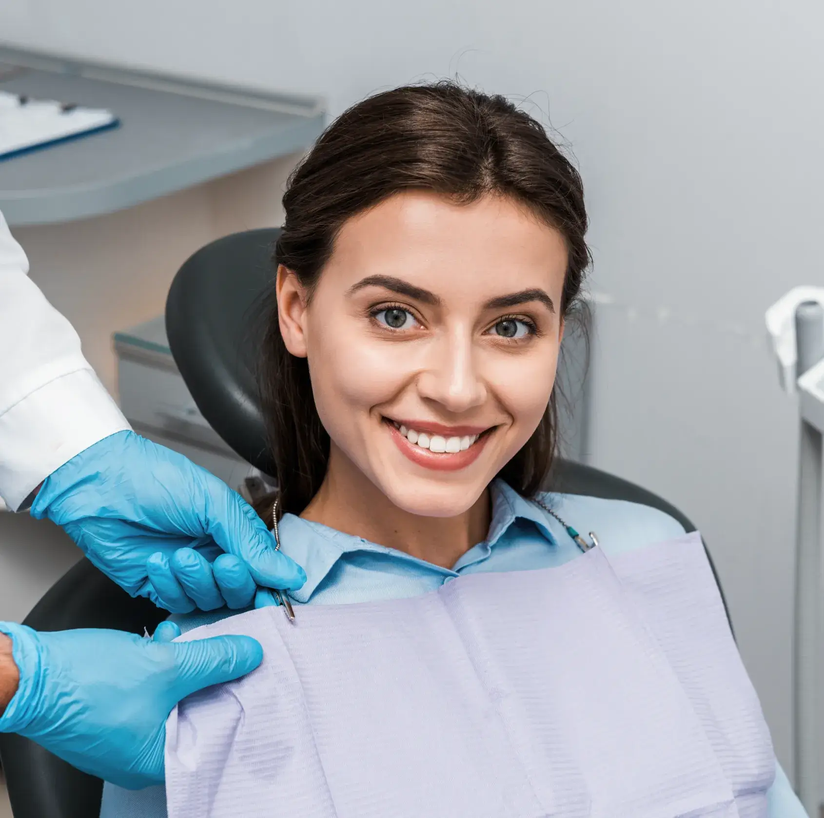 A smiling woman sitting in a dentist chair.