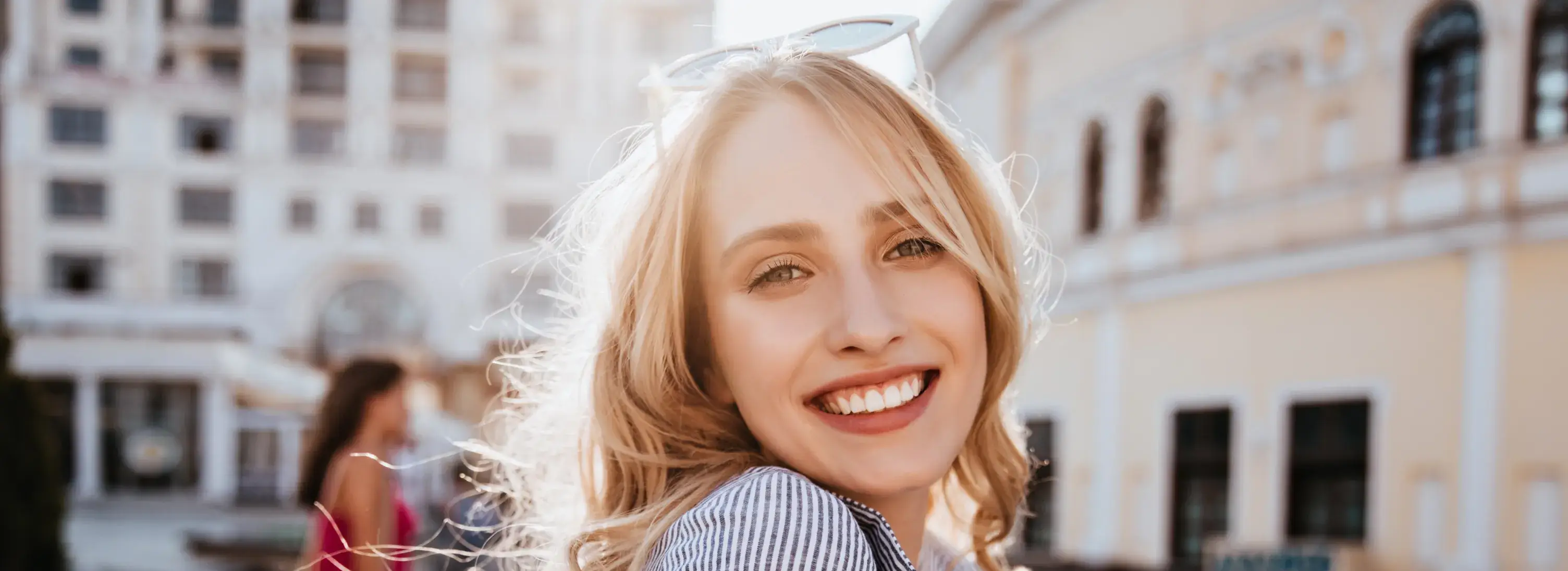A woman with blonde hair and sunglasses smiling.