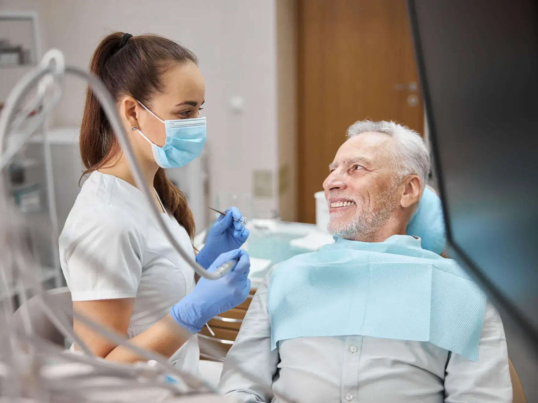 A woman in a dentist chair with a man in a mask.