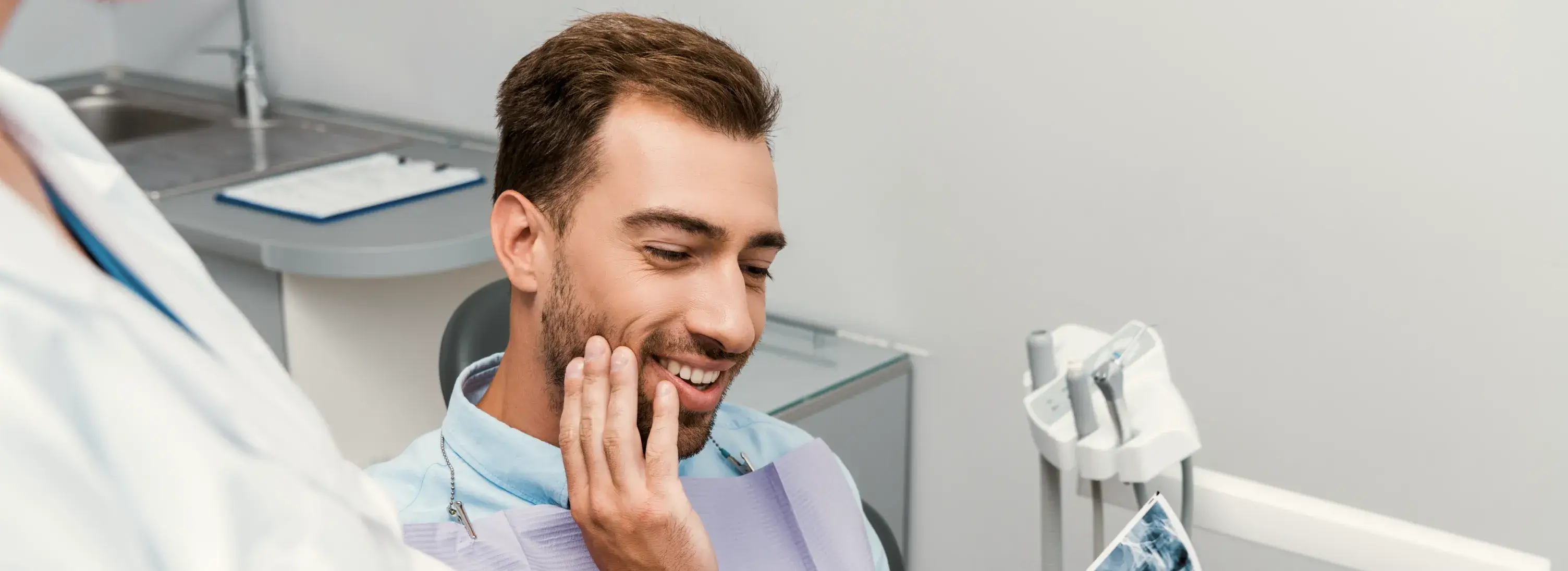 A man in a dentist chair smiling at another man.