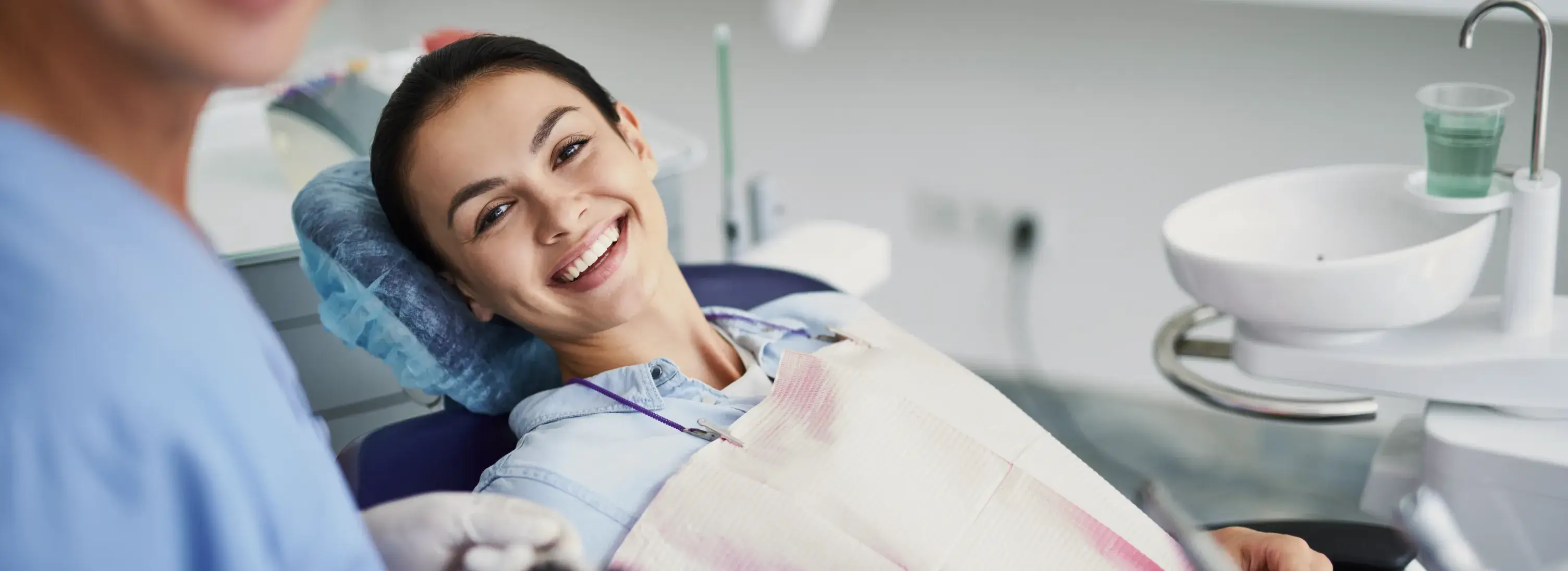 A woman sitting in a dentist chair smiling.