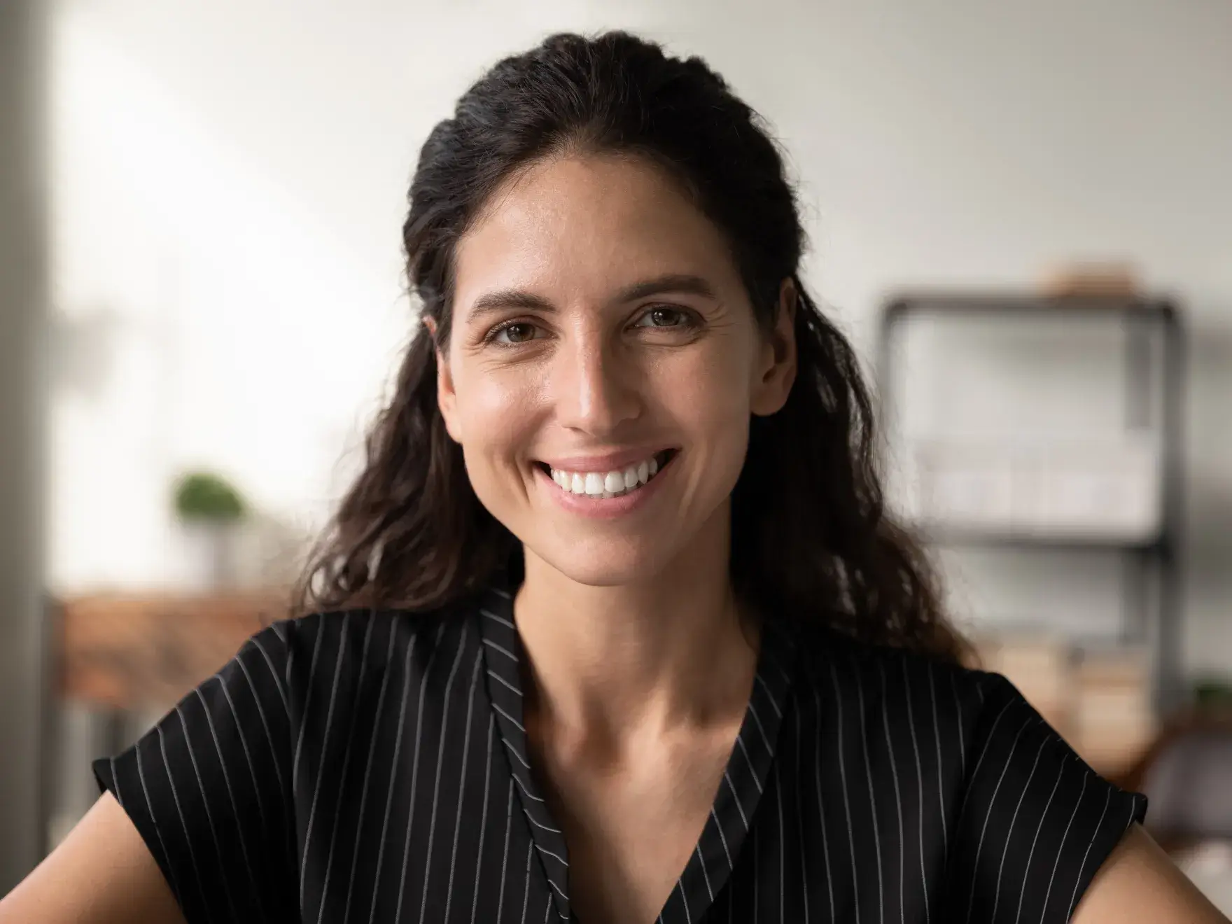 A smiling woman in a black and white shirt.