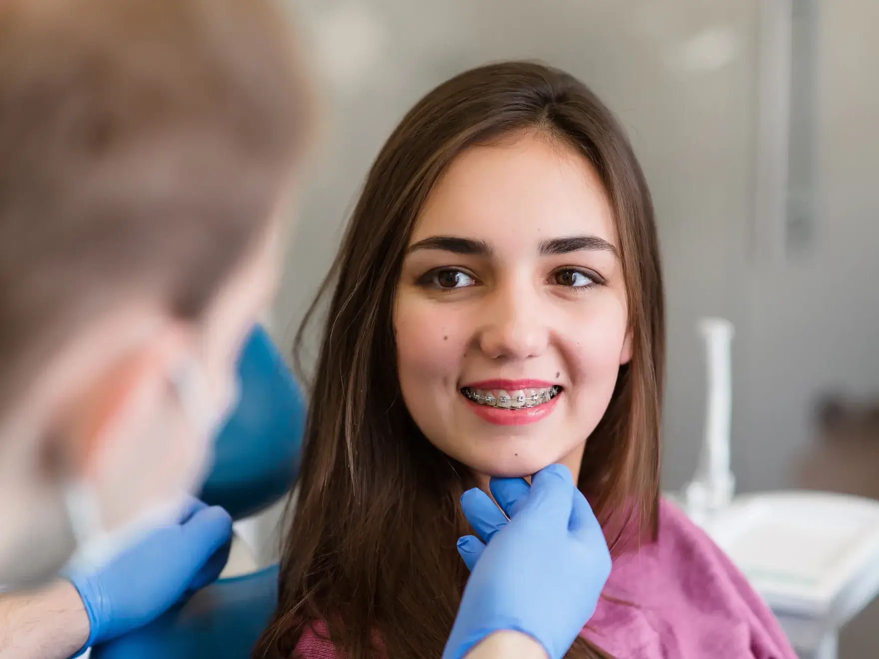 A woman getting her teeth brushed by a dentist.