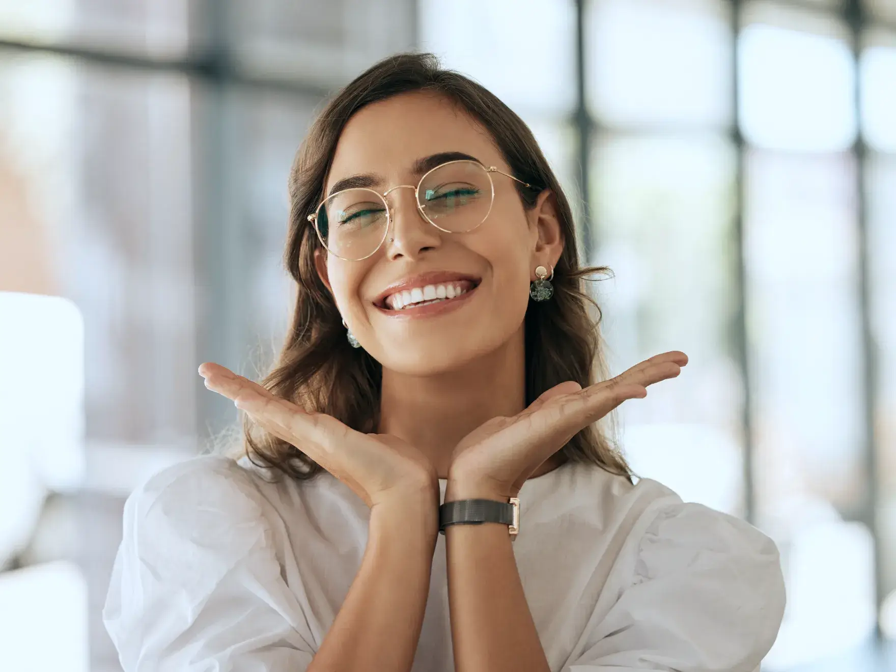A woman wearing glasses making a gesture with her hands.