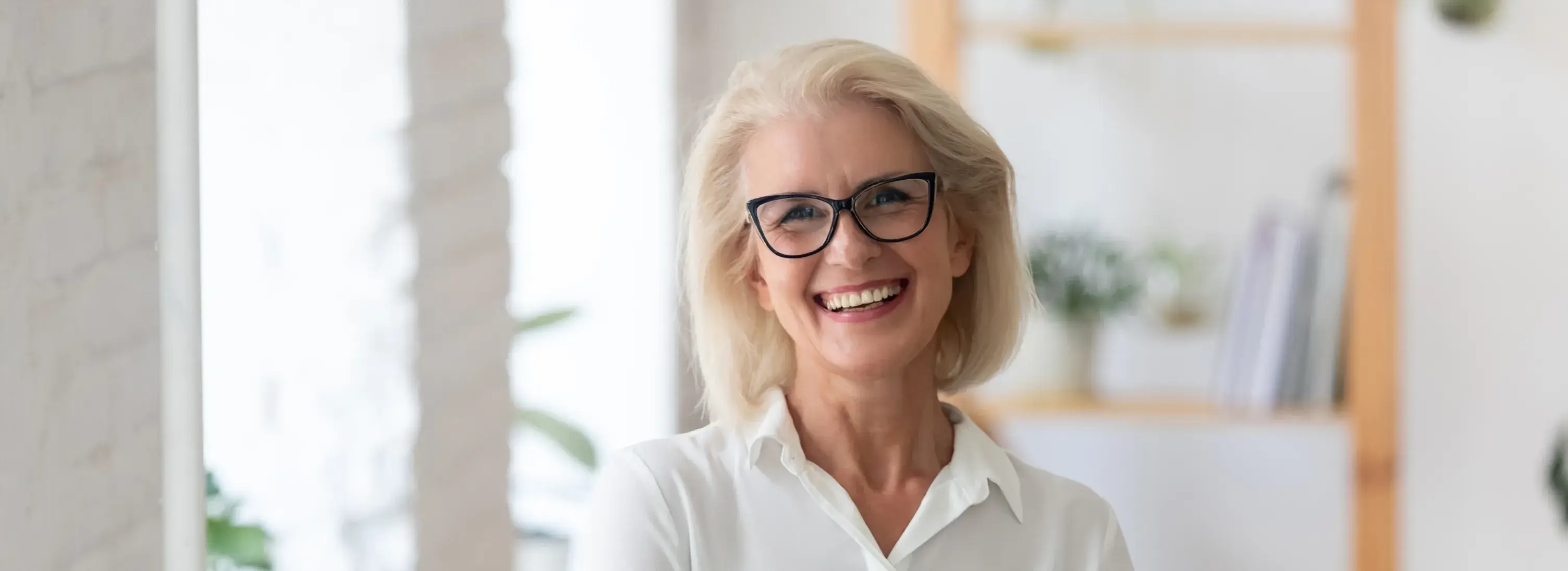 An older woman wearing glasses smiling at the camera.