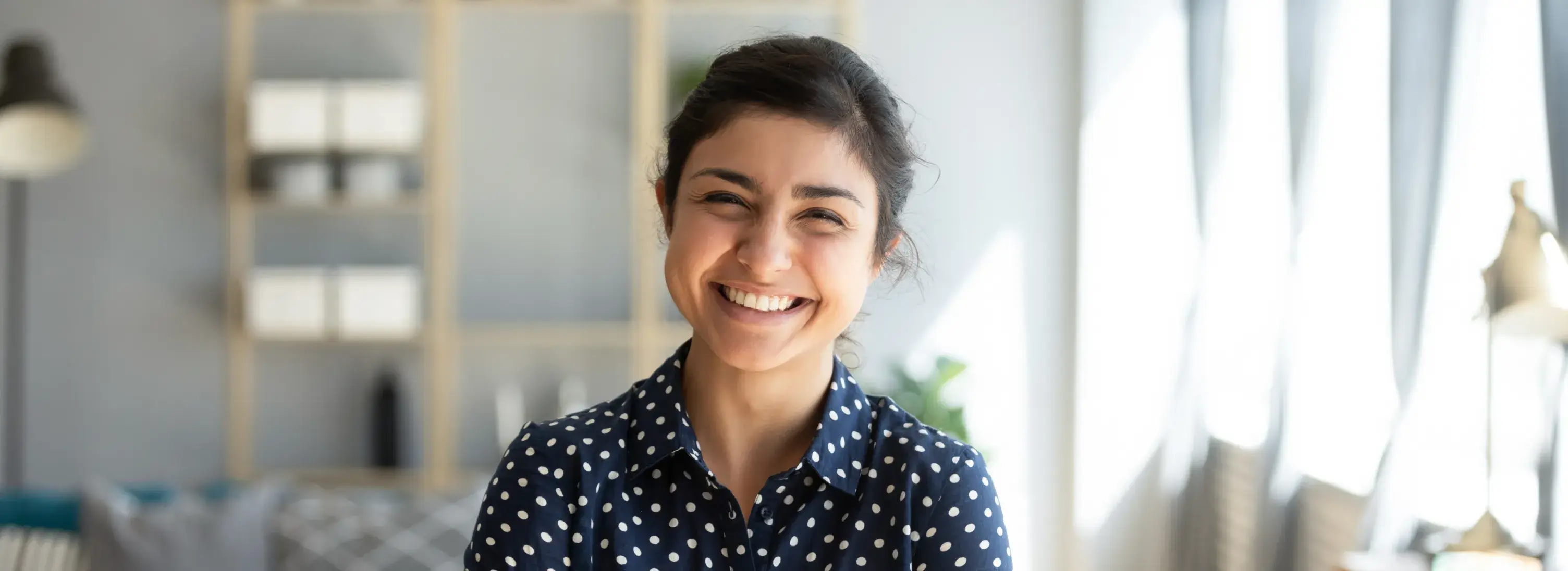 A smiling woman in a polka dot shirt.