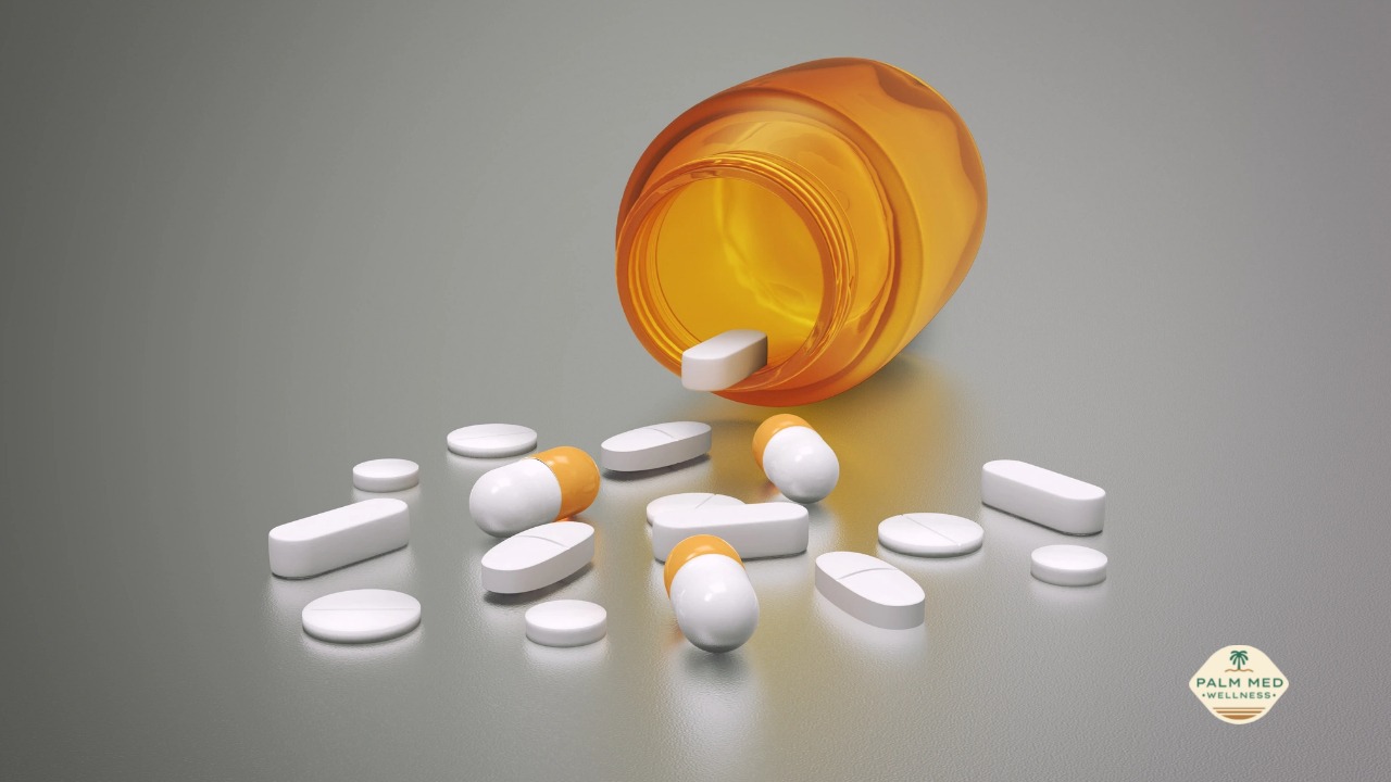 An orange pill bottle tipped over, with colorful pills spilling out onto a white surface.