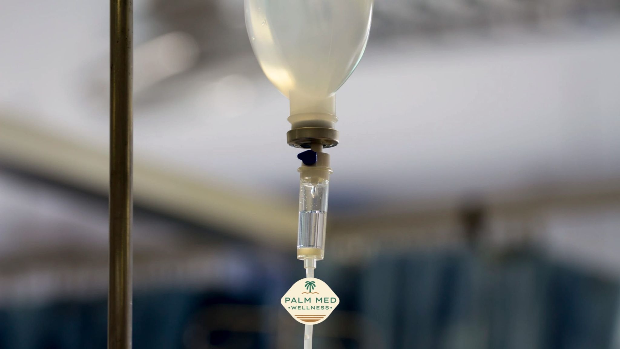 A clear IV drip hanging from a hospital bed, with a soft focus on the medical equipment in the background.