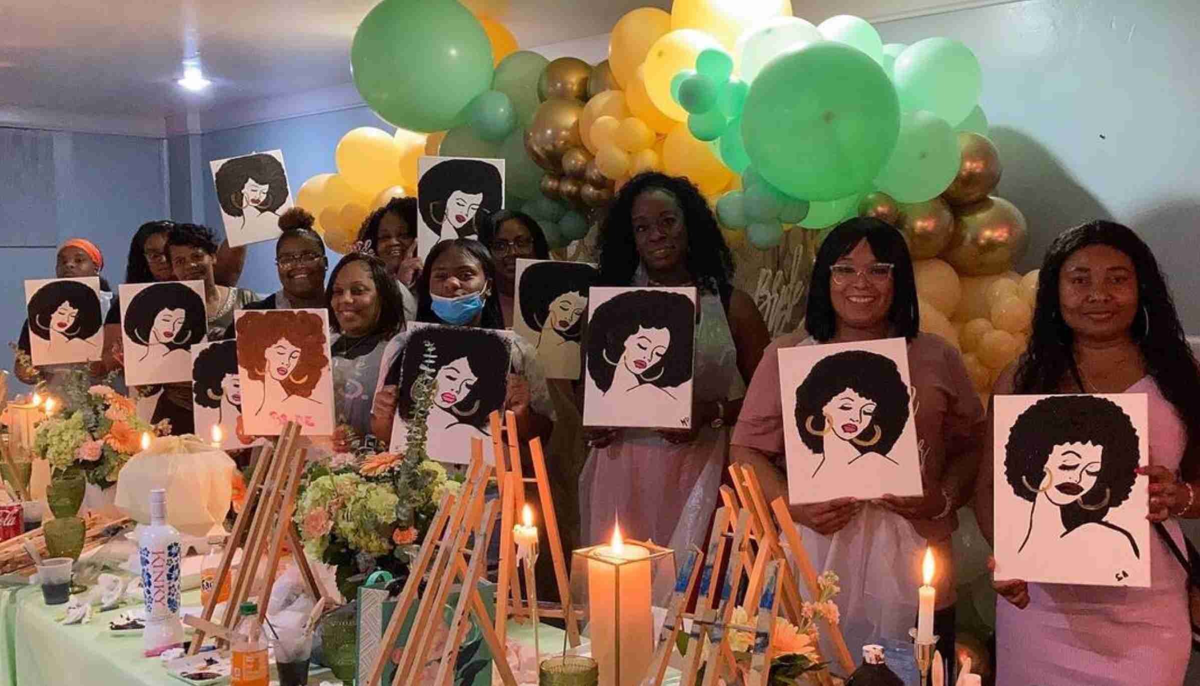 A group of women holding the paintings they created at a mobile paint and sip at their event home.