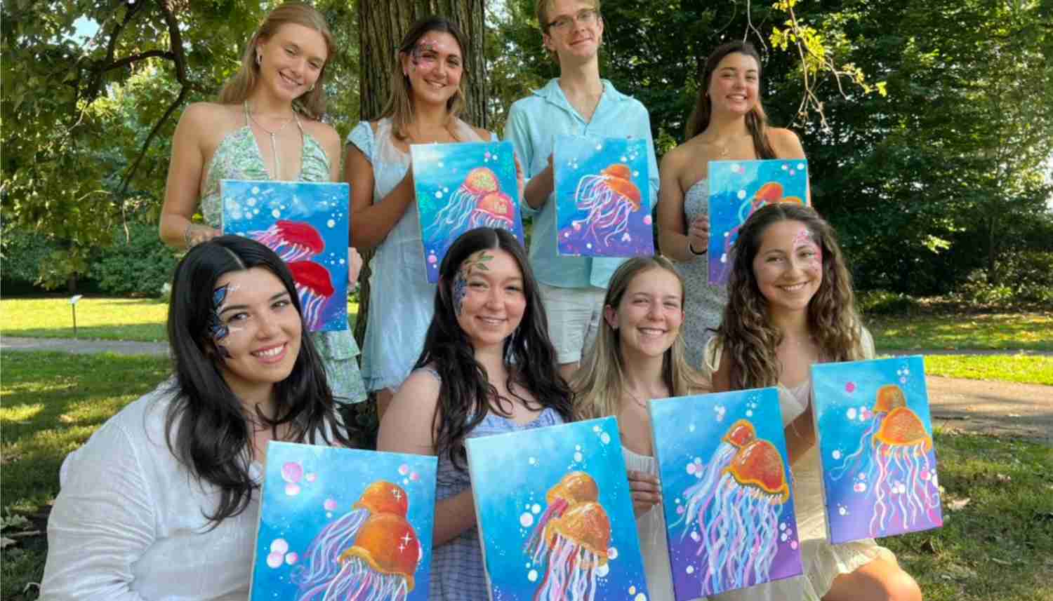 Group of people celebrating a birthday party in a dimly lit room with a glowing cake and festive decorations.