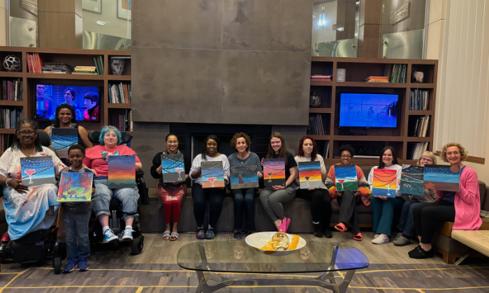 A large group of people holding their cupcake paintings that they made at a mobile paint and sip at their gymnastics studio.