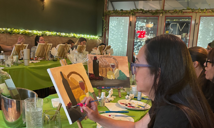 a group of people holding paintings that they created of their pets during a mobile paint and sip at their office.