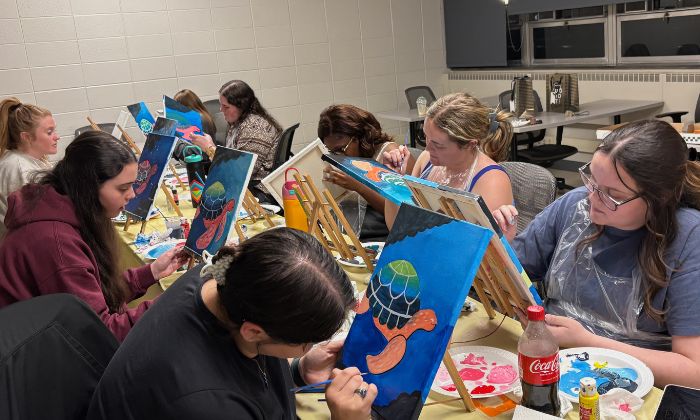a group of women holding wine bottles that they painted at a mobile paint and sip for their Galentine's Celebration