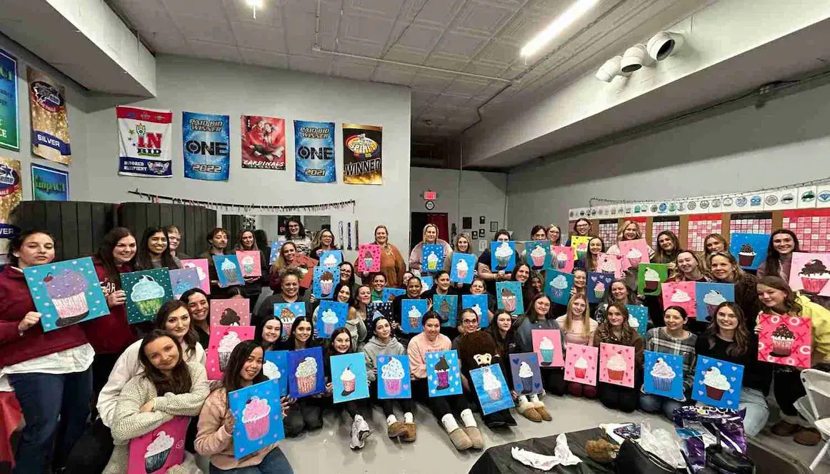 A large group of people holding their cupcake paintings that they made at a mobile paint and sip at their gymnastics studio.