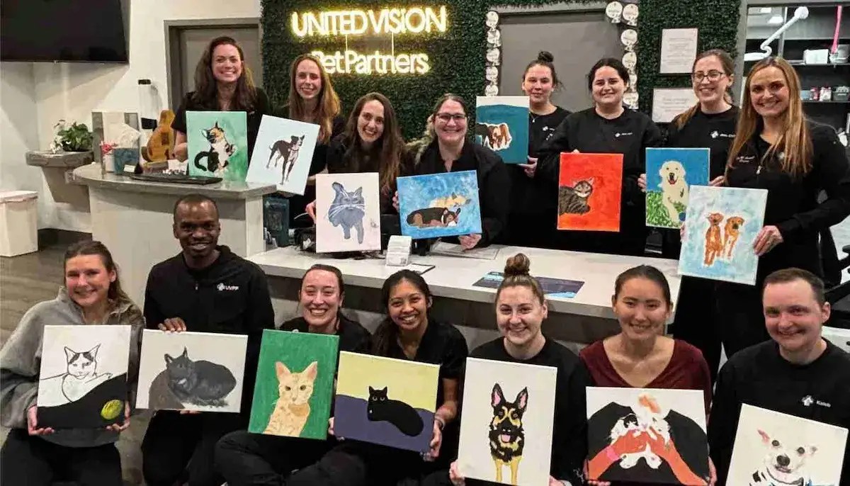 a group of people holding paintings that they created of their pets during a mobile paint and sip at their office.