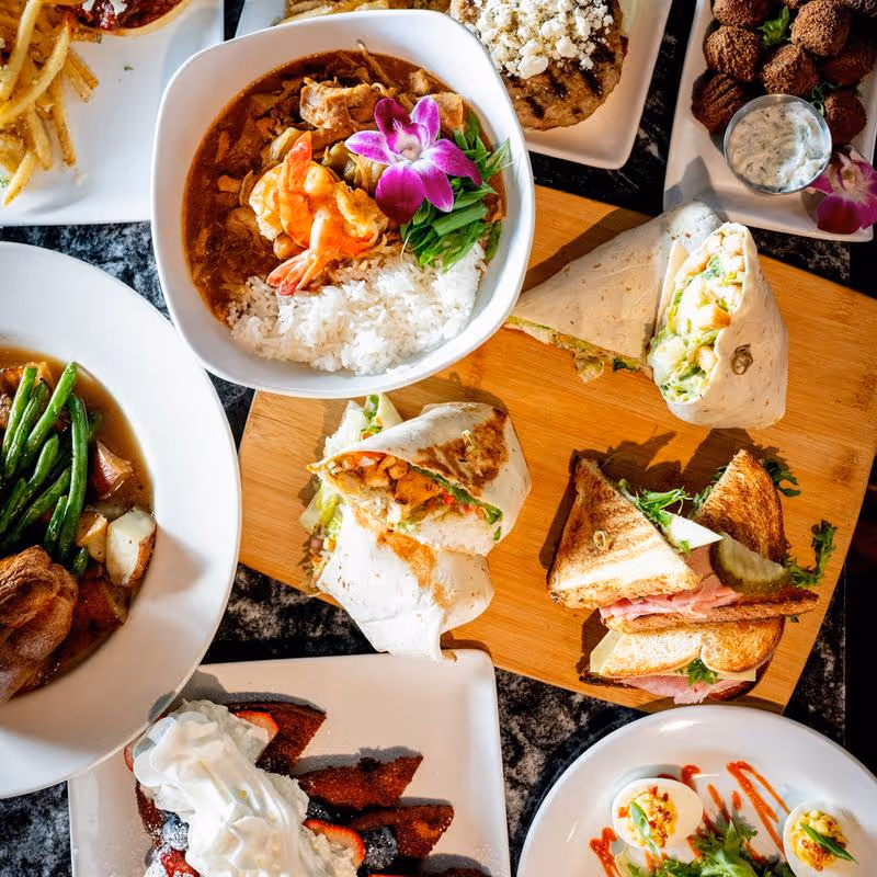 A table full of food including sandwiches, soup, and fries.