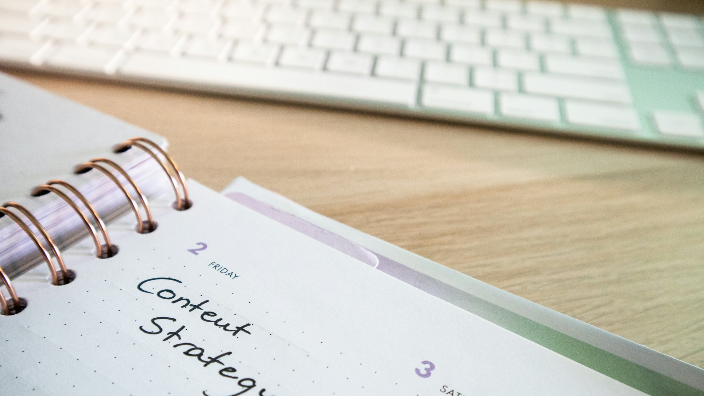 A desk with a planner reading content strategy next to a keyboard