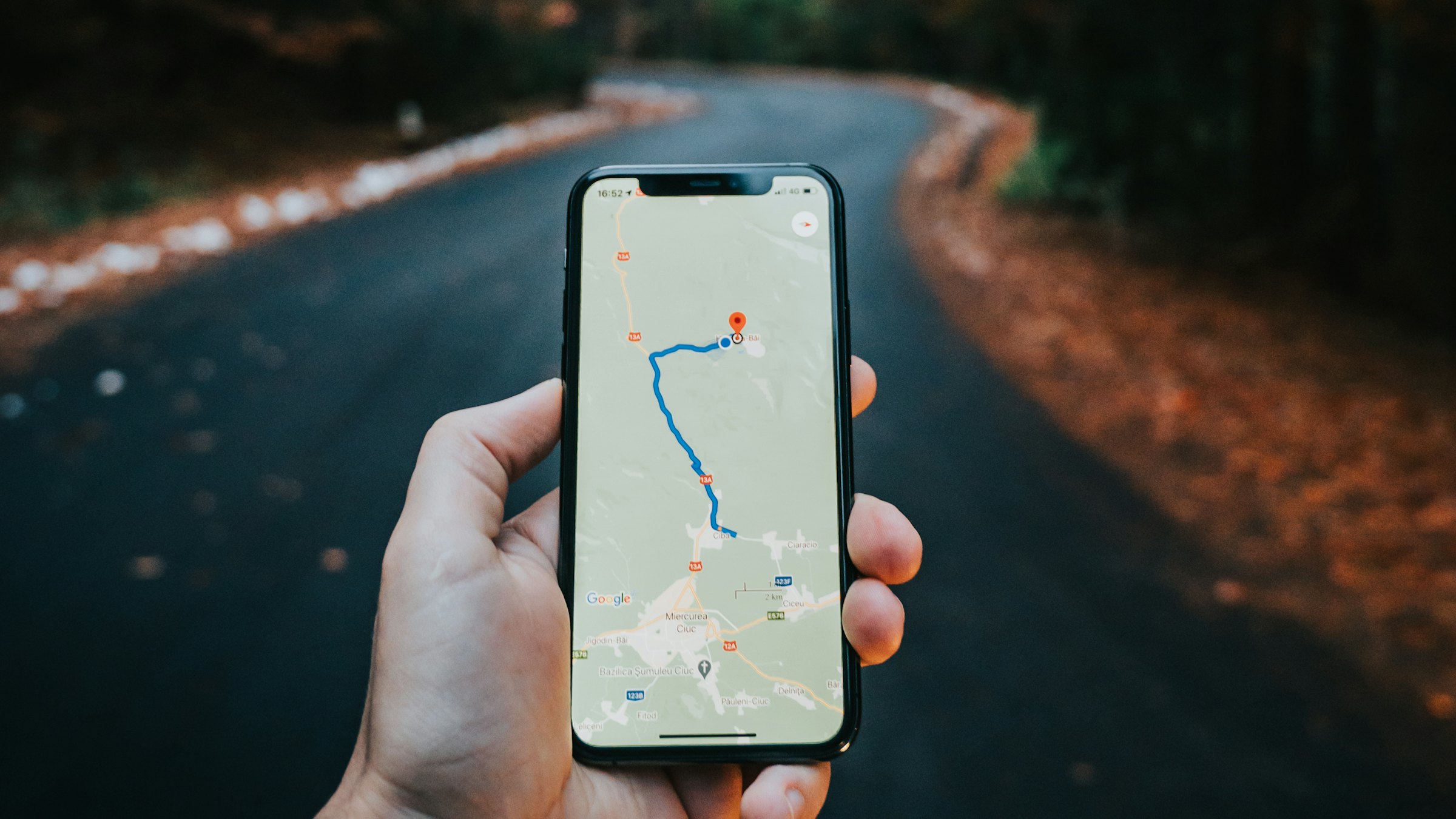 A hand holding a smartphone displaying a navigation map